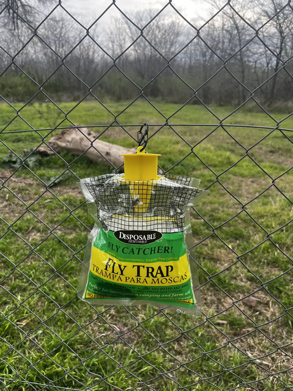 Trampa VIREO colgada de un alambrado, con un campo de fondo
